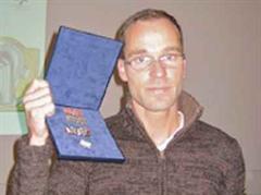 Der Künstler Pascal Kottmann posiert mit der Sieger-Blaggedde.